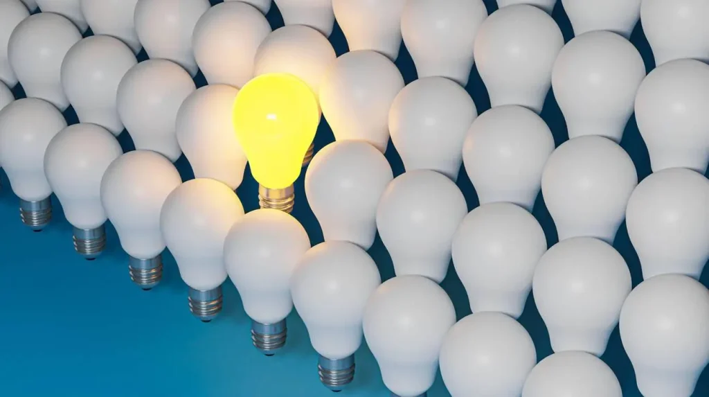 Lit yellow bulb standing out among white bulbs, symbolizing a personalized digital marketing solution.